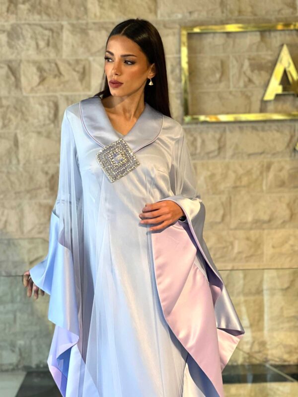 The hand-embroidered details add a touch of artisanal craftsmanship, while the soft tulle draping enhances movement, creating a dreamy, fluid effect. Whether worn as a statement piece or layered with Ayman Lahmouni’s signature accessories, this abaya is designed to captivate.