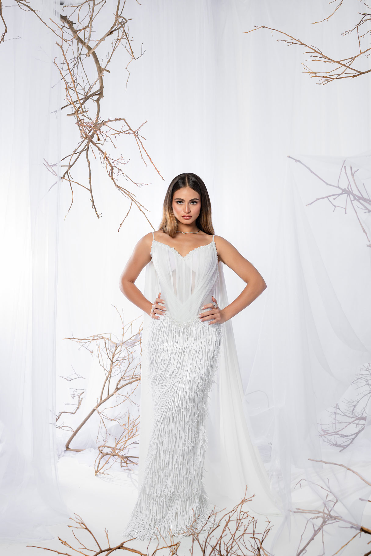 Ivory Mirage Dress a graceful white gown layered in sheer tulle over a texture fringed skirt.